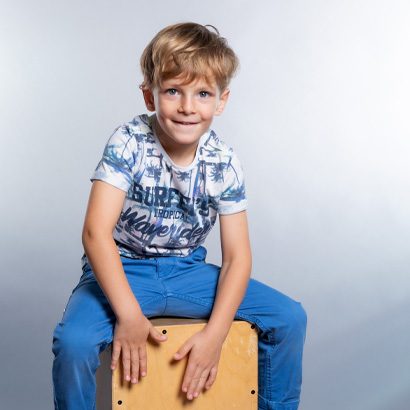 Kind sitzt auf Cajon (Schlaginstrument)